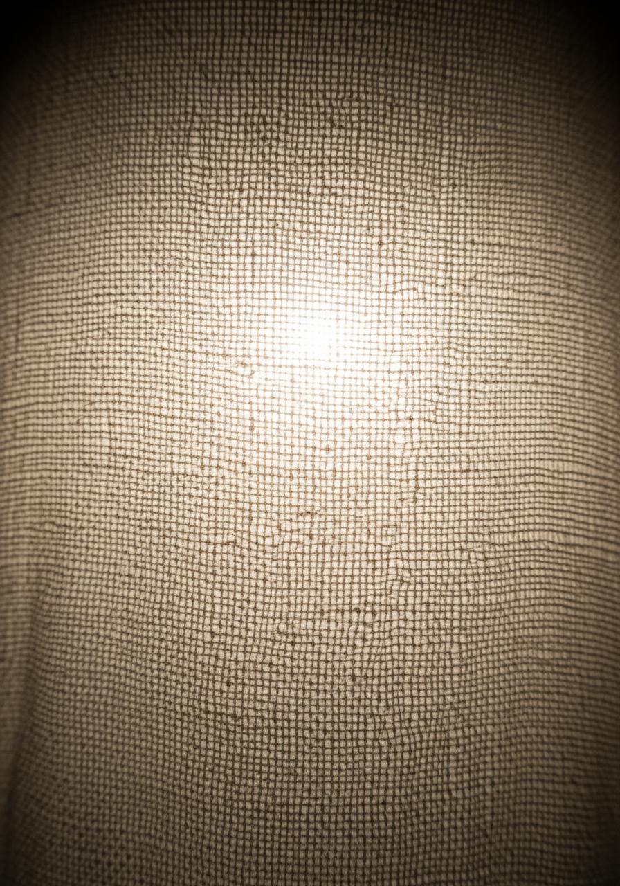 Un tissu en lin de basse qualité, fin et transparent, à contre-jour pour révéler sa faible densité et son tissage lâche.