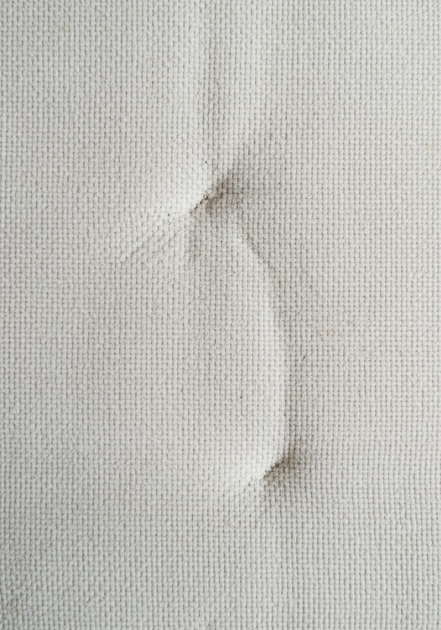 Prise de vue macro de la texture d'un vieux tissu de matelas, montrant une légère décoloration et usure.