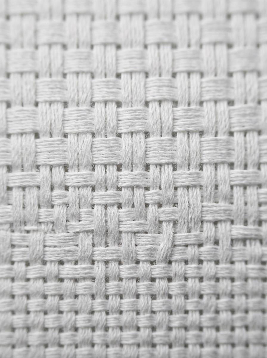 Une vue macro d'un tissu en percale de coton, montrant clairement le tissage serré et mat caractéristique, un fil dessus, un fil dessous.