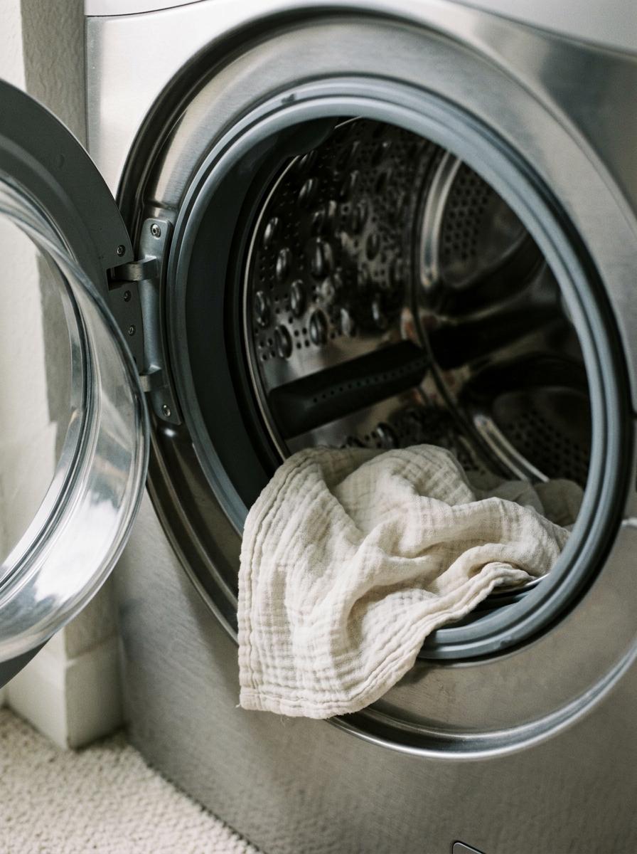 Un vêtement en gaze de coton placé délicatement à l'intérieur d'un tambour de machine à laver avant le lavage.