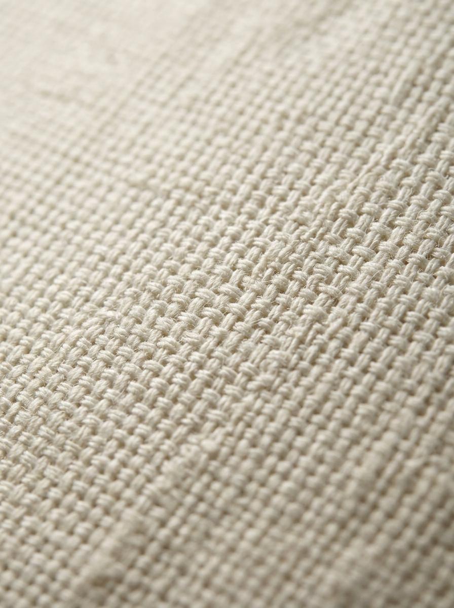 Vue macro du tissage serré et régulier d'un drap en percale de coton, mettant en évidence sa haute qualité de fabrication.