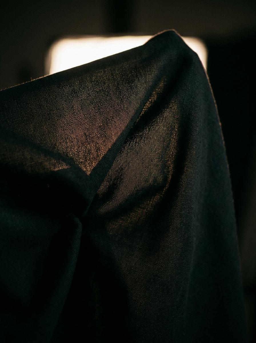Une feuille de tissu dense tenue contre la lumière, ne montrant presque aucune transparence.