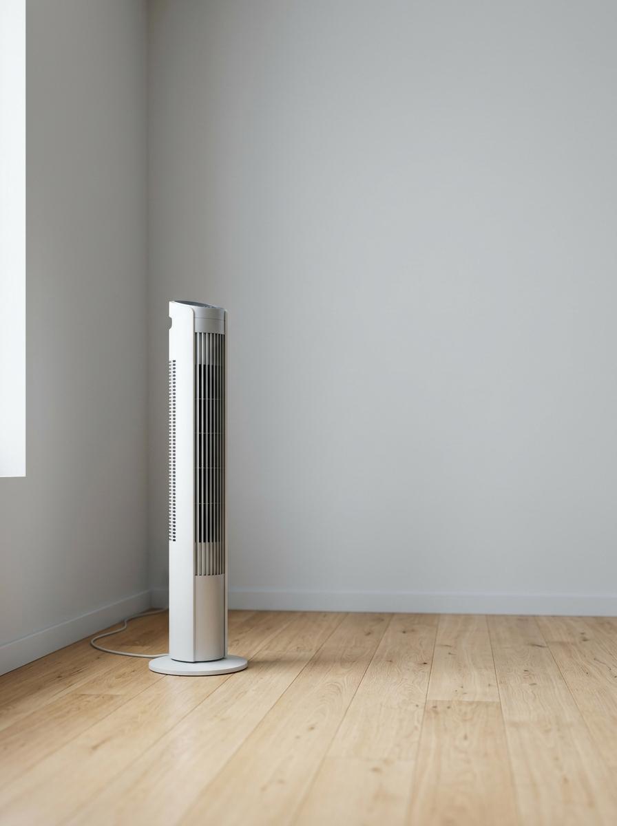 Un ventilateur sur pied design et moderne dans le coin d'une pièce minimaliste, illustrant un plan d'action réussi pour un été serein.