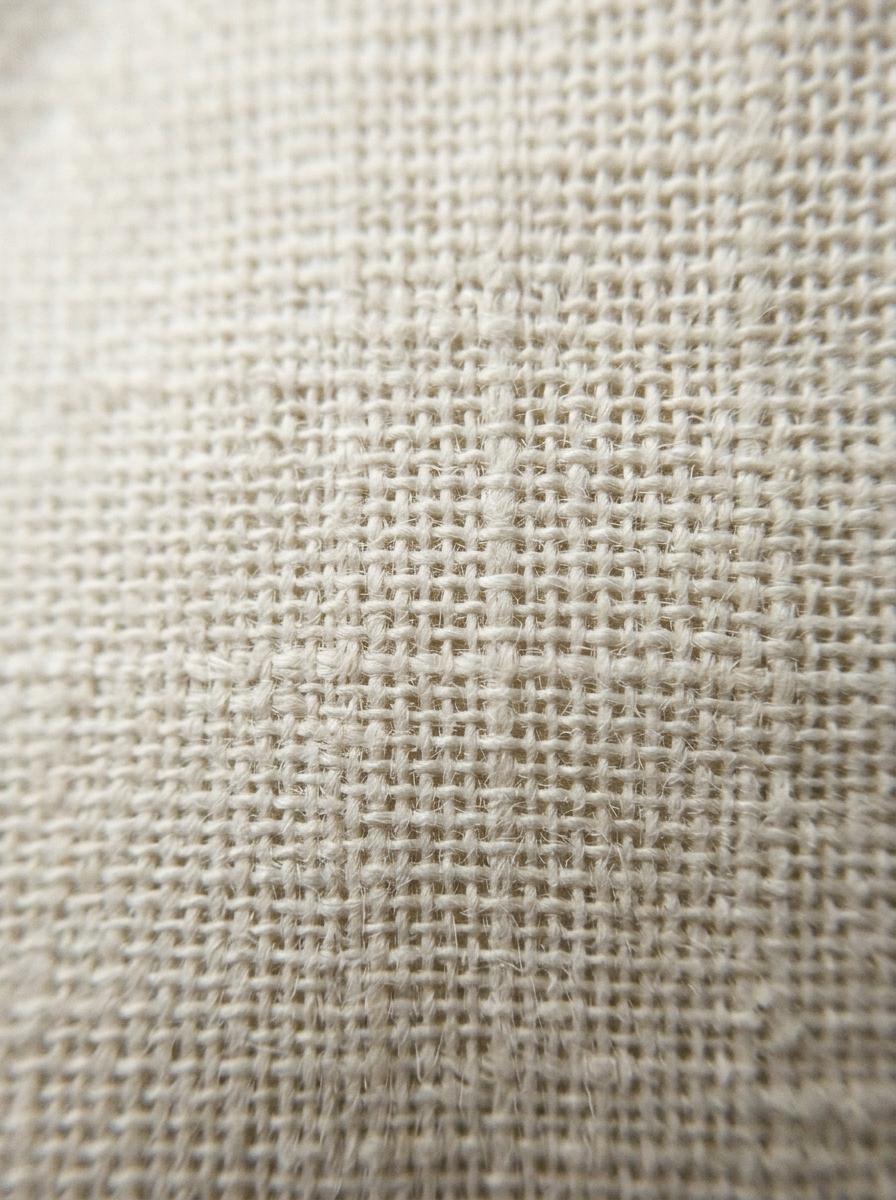 Vue macro du tissage d'un drap en percale, mettant en évidence la structure en grille qui favorise la circulation de l'air.