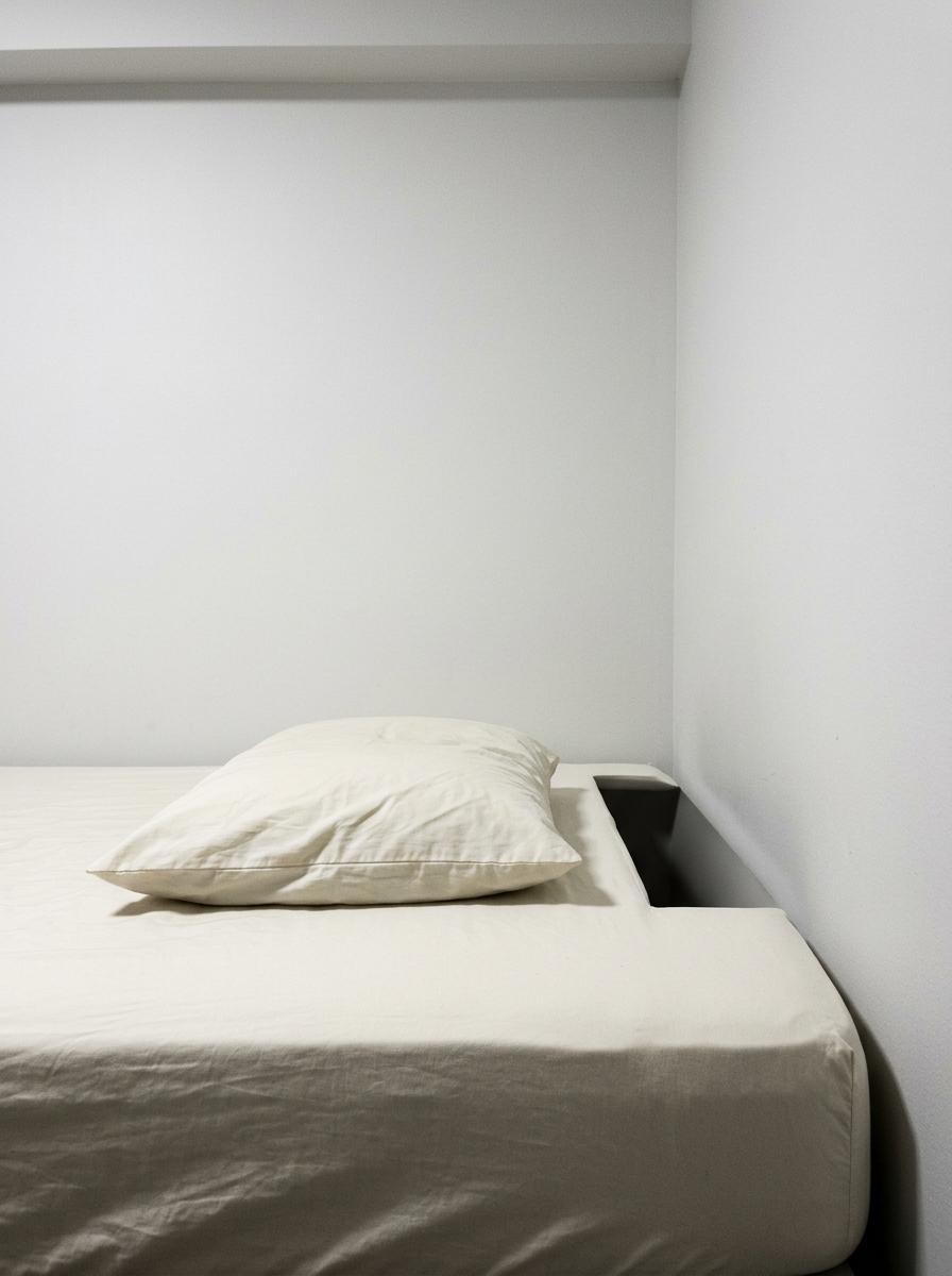 Un oreiller trop plat sur un matelas, montrant l'espace vide qui cause un mauvais alignement pour un dormeur sur le côté.