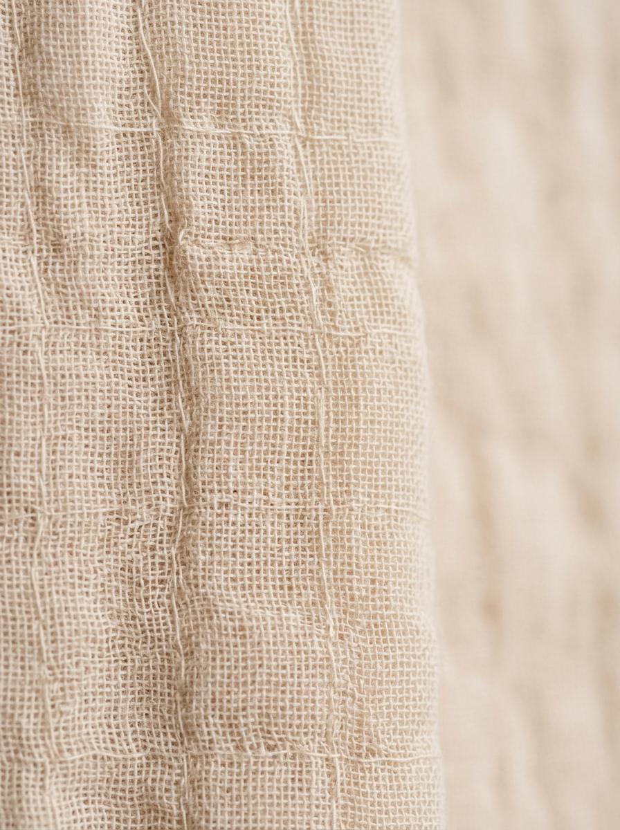 Macro photo de la texture d'un tissu en double gaze de coton, montrant le tissage délicat et l'aspect gaufré.