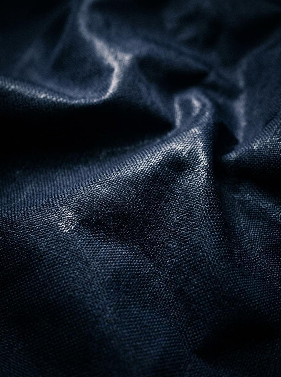 Gros plan sur un tissu synthétique bleu foncé, d'aspect dense et légèrement brillant, suggérant une matière qui retient la chaleur.