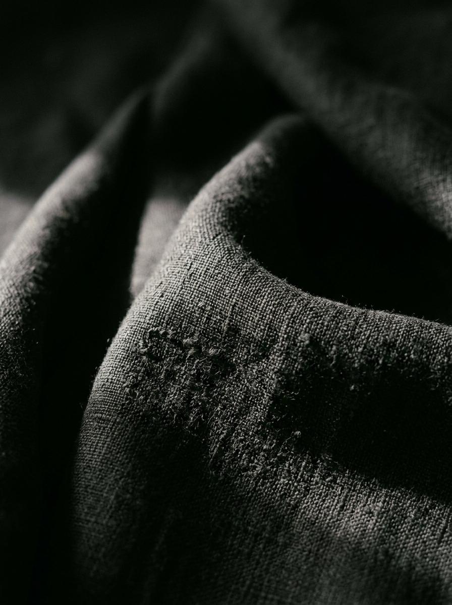 Gros plan sur un tissu en lin de haute qualité, avec un éclairage dramatique qui accentue la texture et la richesse du tissage.