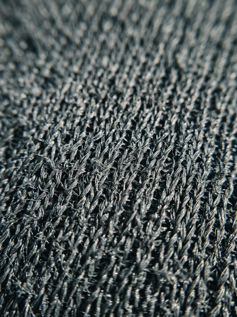 Prise de vue macro d'un tissu synthétique rugueux et irritant, montrant la texture abrasive des fibres qui peut causer des démangeaisons.
