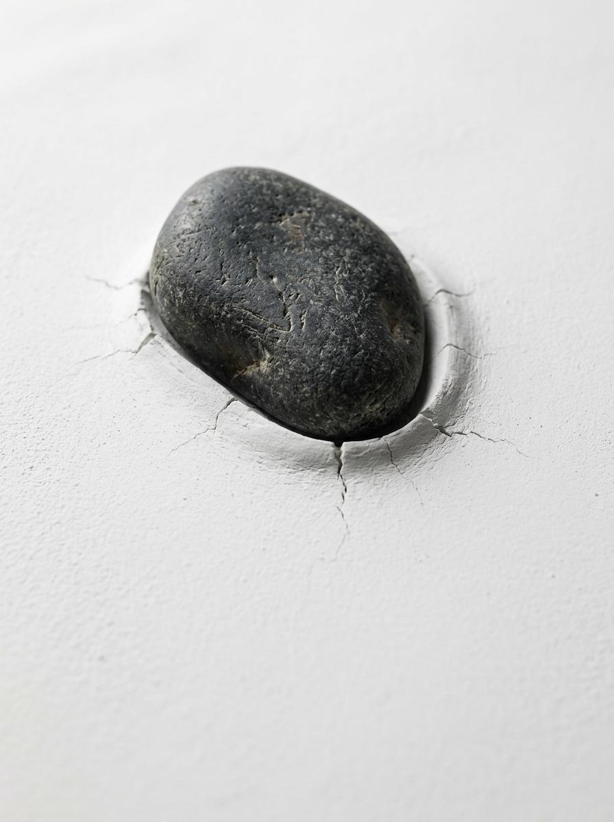 Un gros plan d'une pierre lourde créant un point de pression sur une surface dure et blanche.