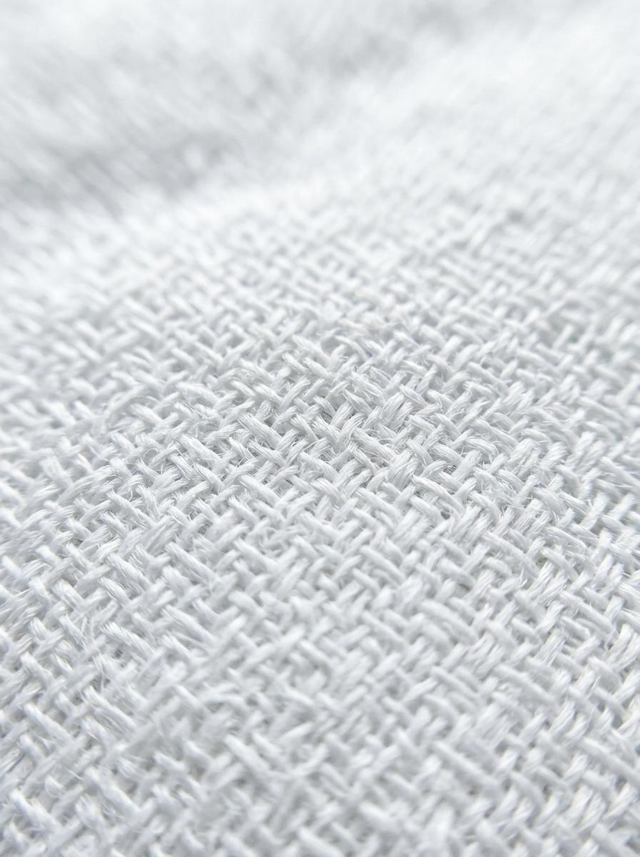 Gros plan sur la texture et le tissage serré d'un tissu de literie blanc et propre, symbolisant la barrière anti-allergènes.