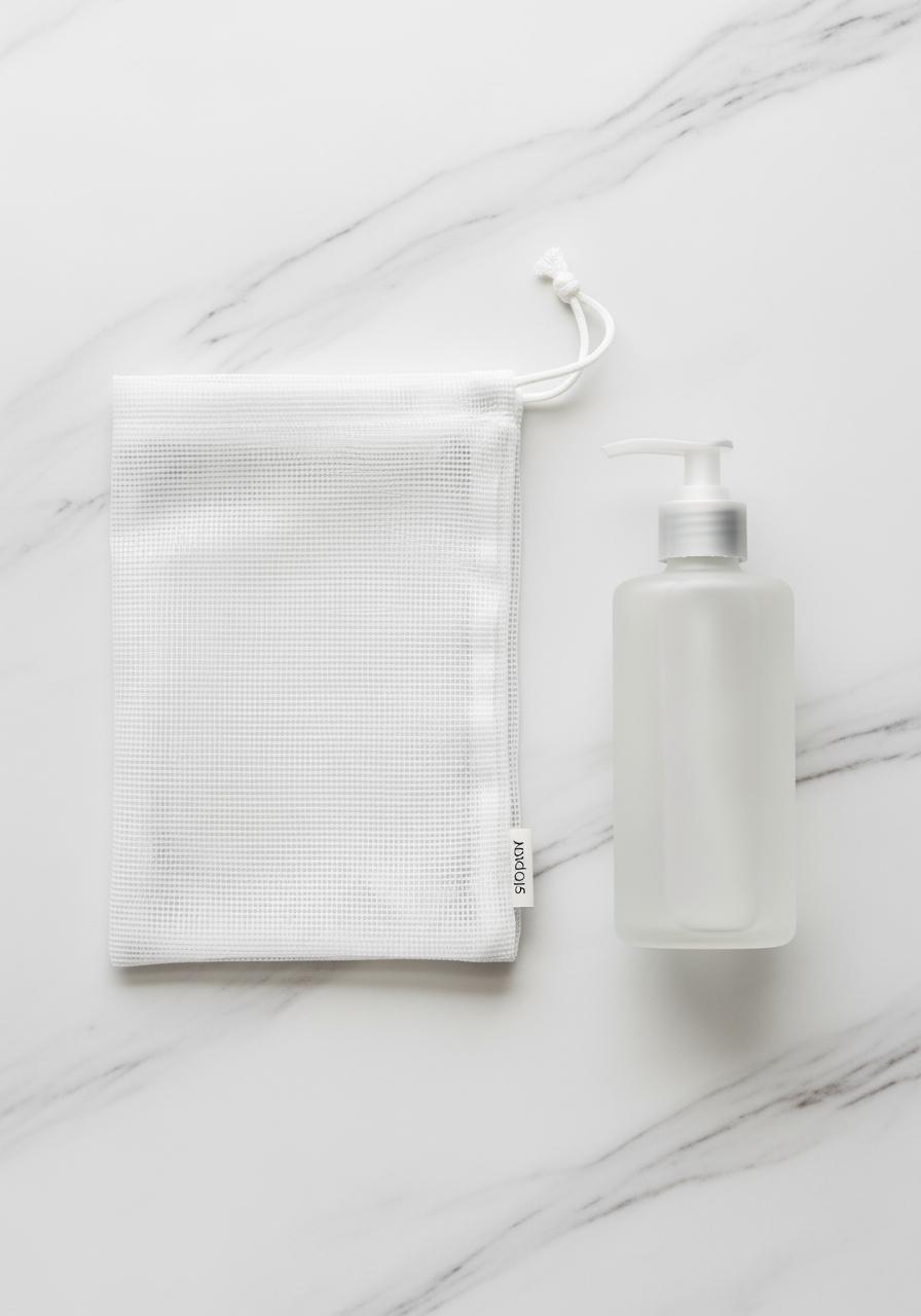 Vue de dessus des indispensables pour le lavage de la soie : un filet de lavage et un flacon de lessive spéciale.
