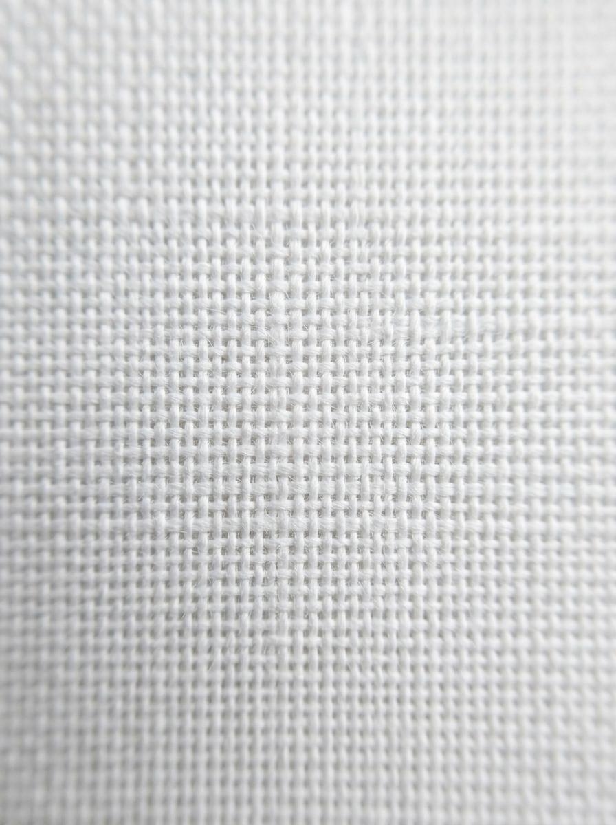 Vue macro d'un tissage de tissu en coton, montrant la grille serrée des fils de chaîne et de trame.